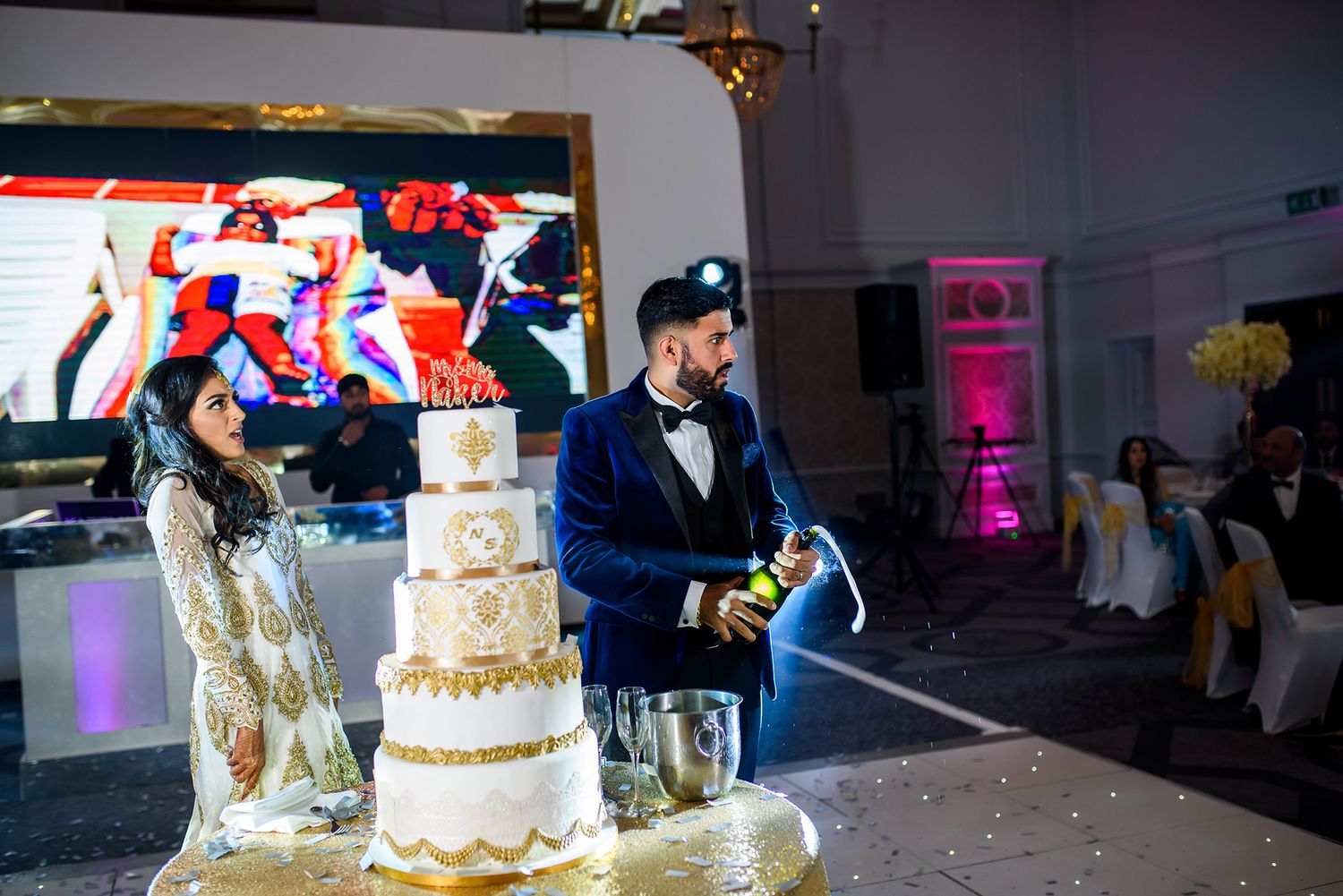 Reception venue with multiple wedding cakes displayed under spotlights.