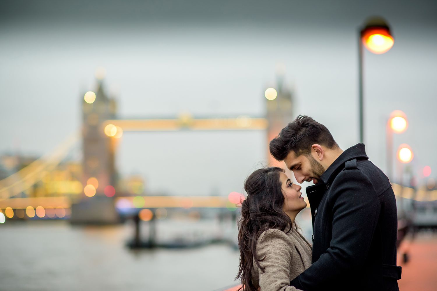 Atmospheric evening photoshoot on London bridge with city lights twinkling in background.