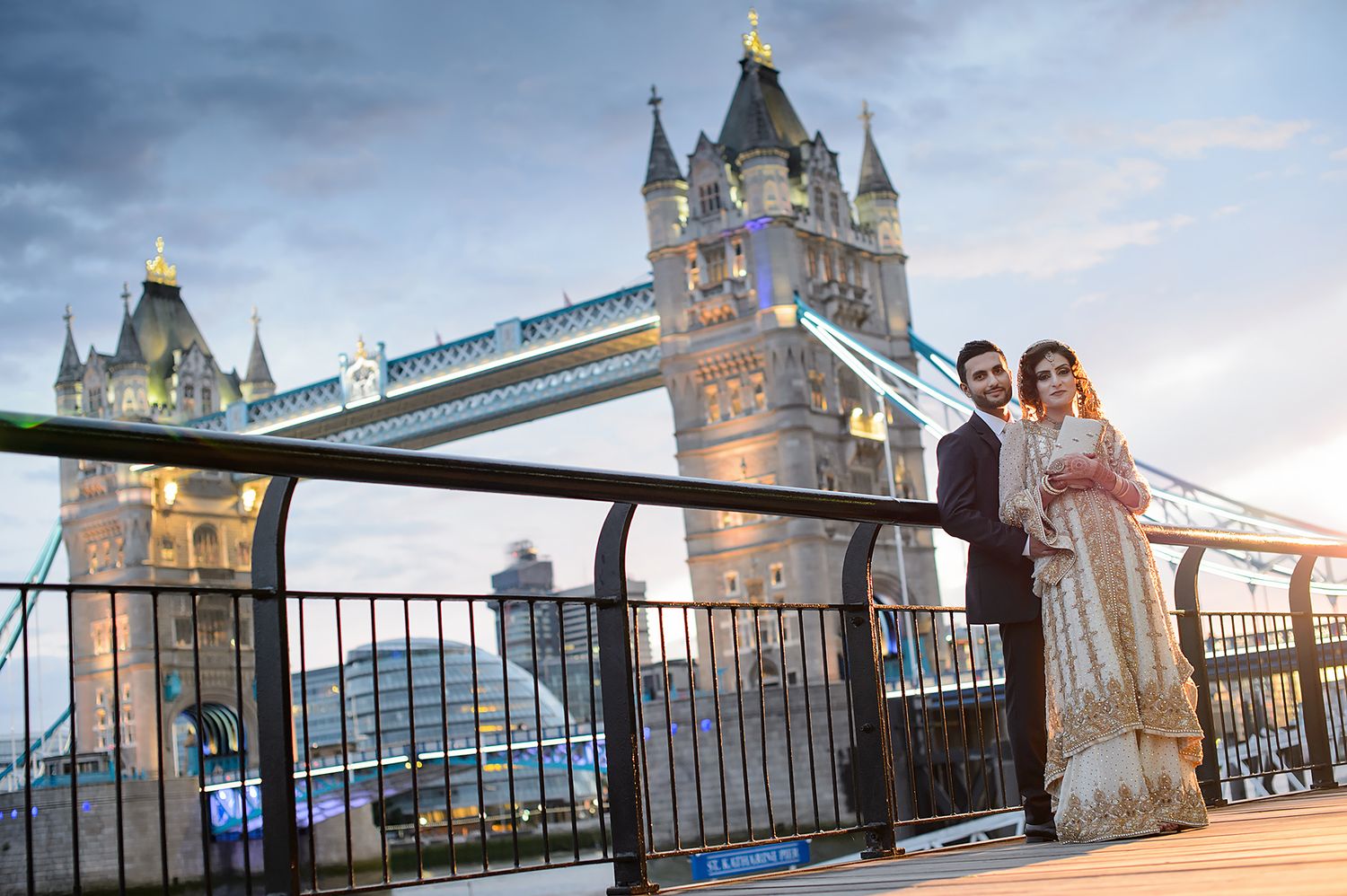 Iconic Tower Bridge in London illuminated at dusk with pedestrians walking across the bridge span.