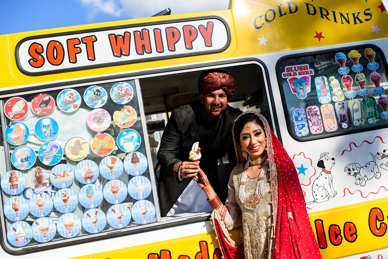 Wedding couple posing by colorful ice cream truck in traditional South Asian attire.
