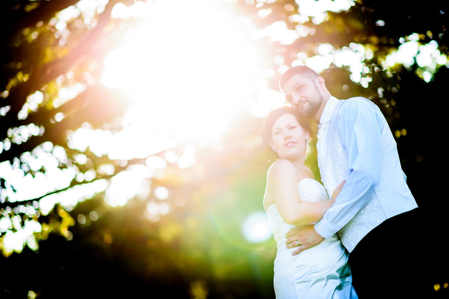 Golden sunlight creates dreamy backlit effect for romantic outdoor wedding portraits.