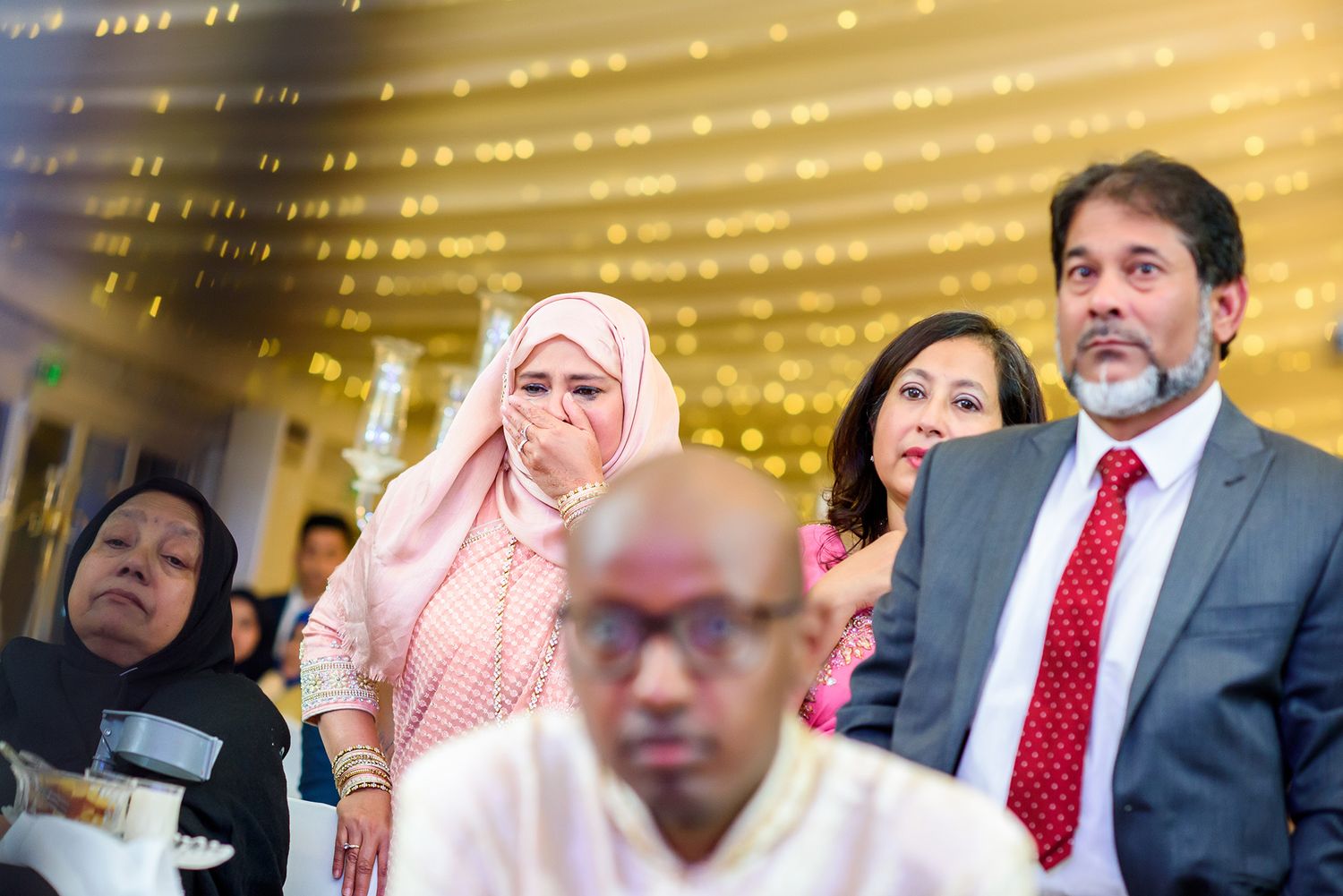 Diverse group of guests at formal event under warm lighting.