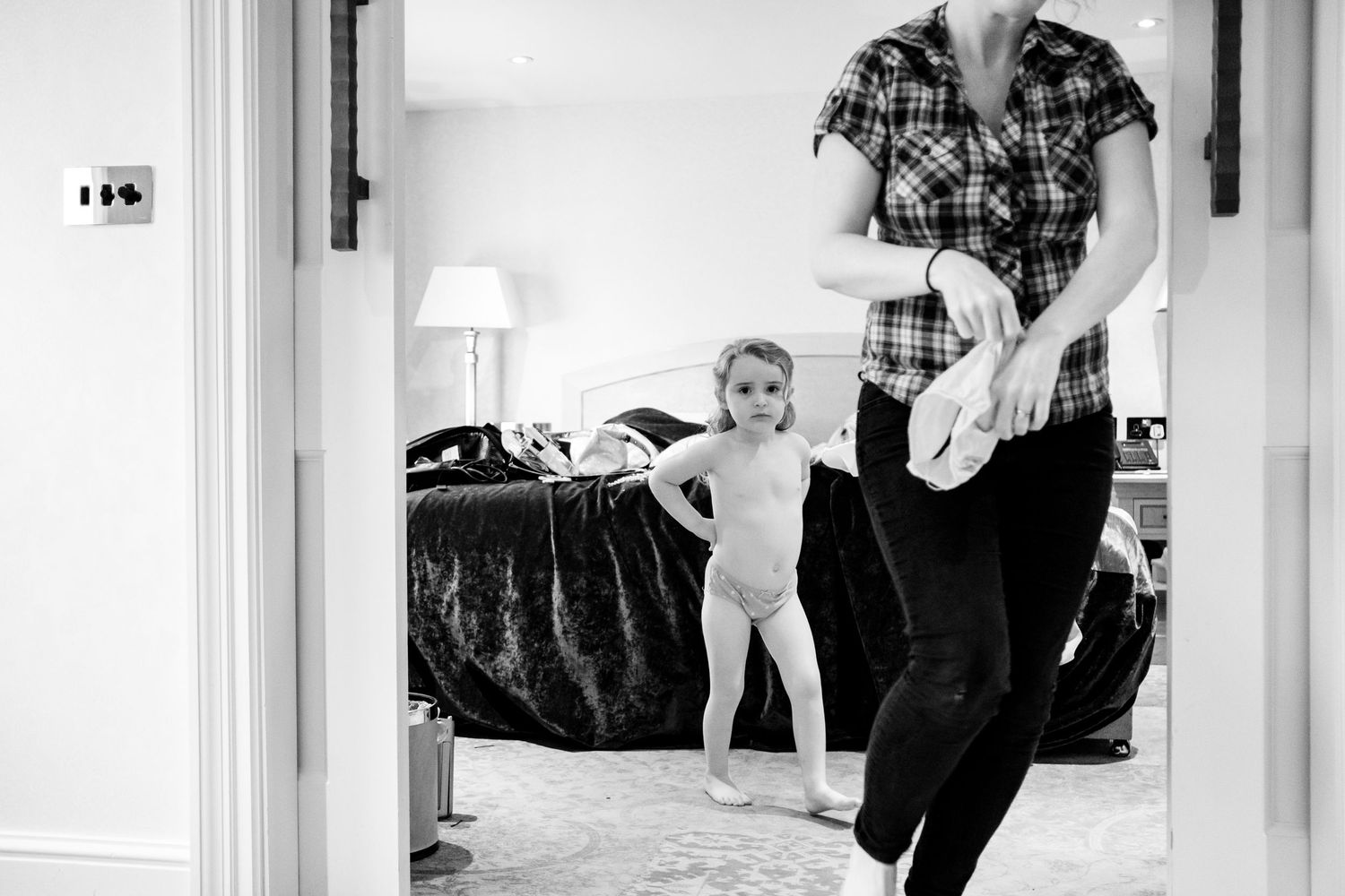 Black and white wedding photos showing preparation moments in a bright room with natural light.