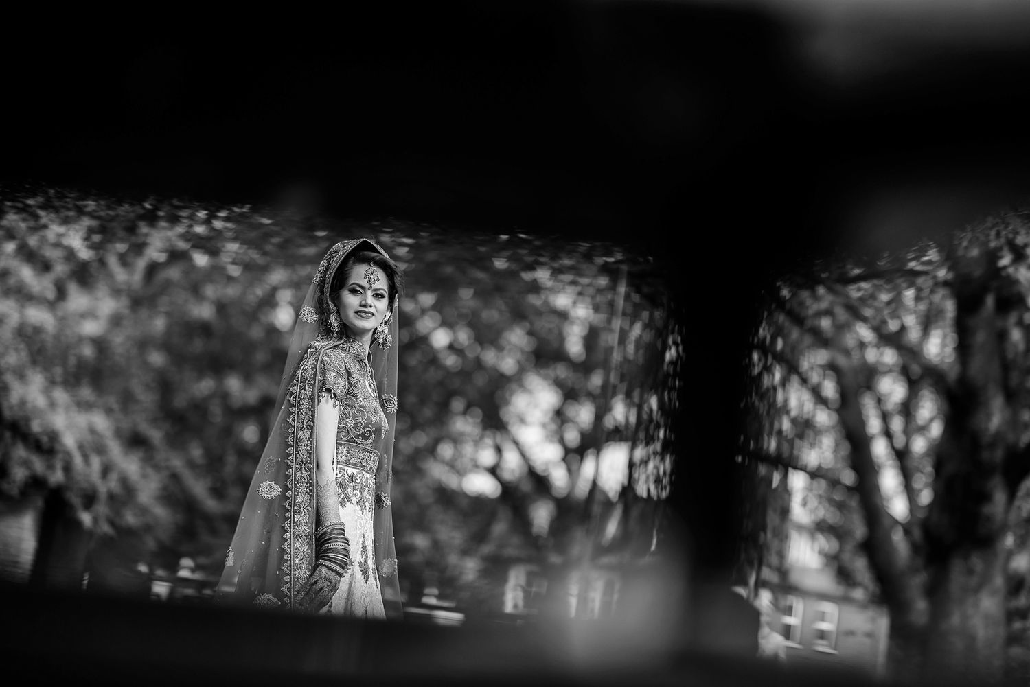 Natural framed portrait shot through garden greenery and shadows.