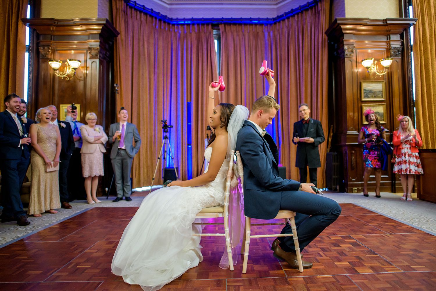 Wedding ceremony reception game with chairs in an elegant ballroom with purple lighting.