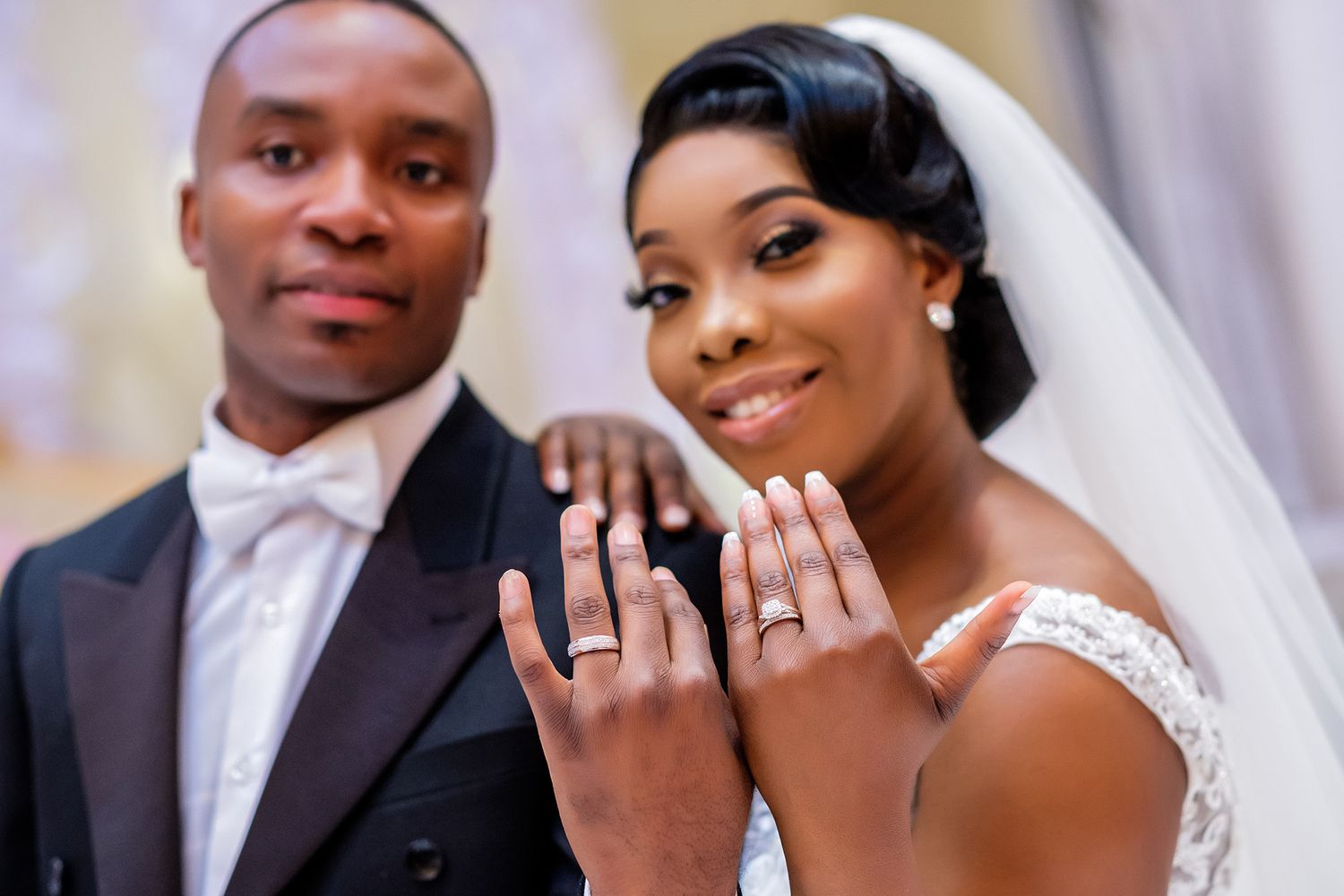Happy couple showing off their wedding rings with bright smiles.