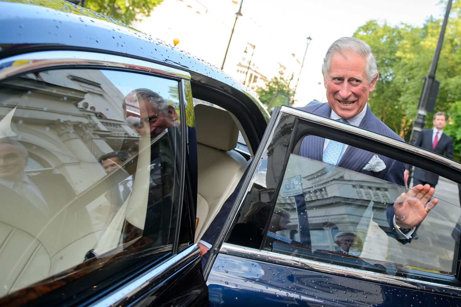 Someone entering a classic black car while expressing joy.