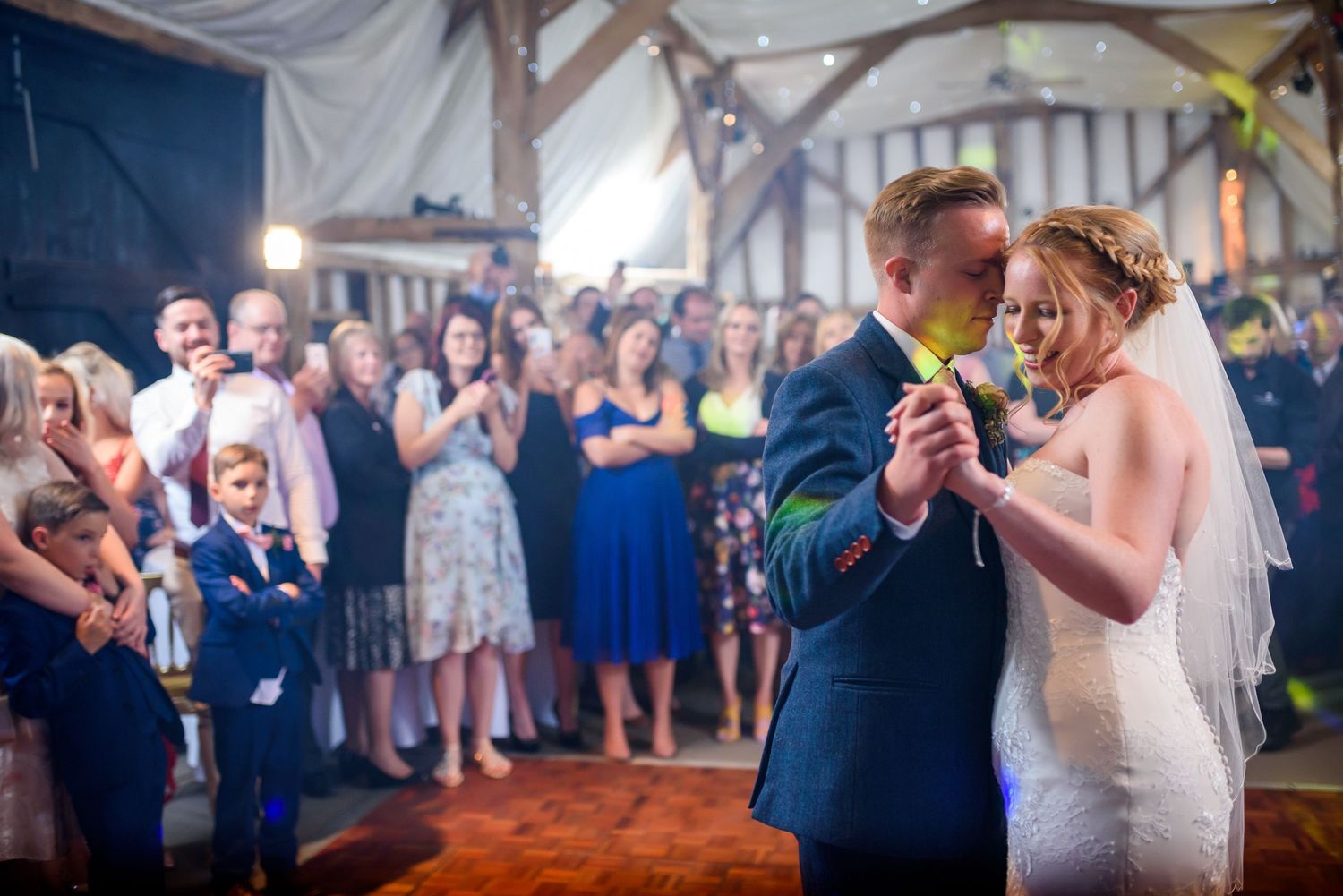 Wedding guests dance and celebrate on a dimly lit dance floor during an evening reception.