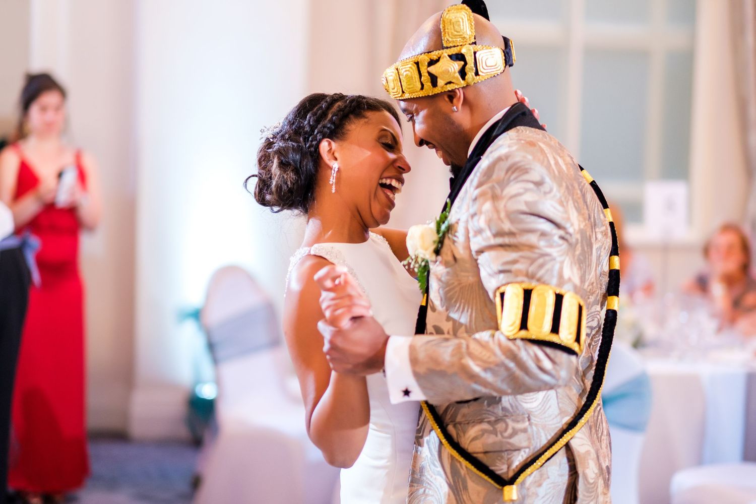 A couple shares their first dance at a wedding reception with the groom wearing a gold crown.