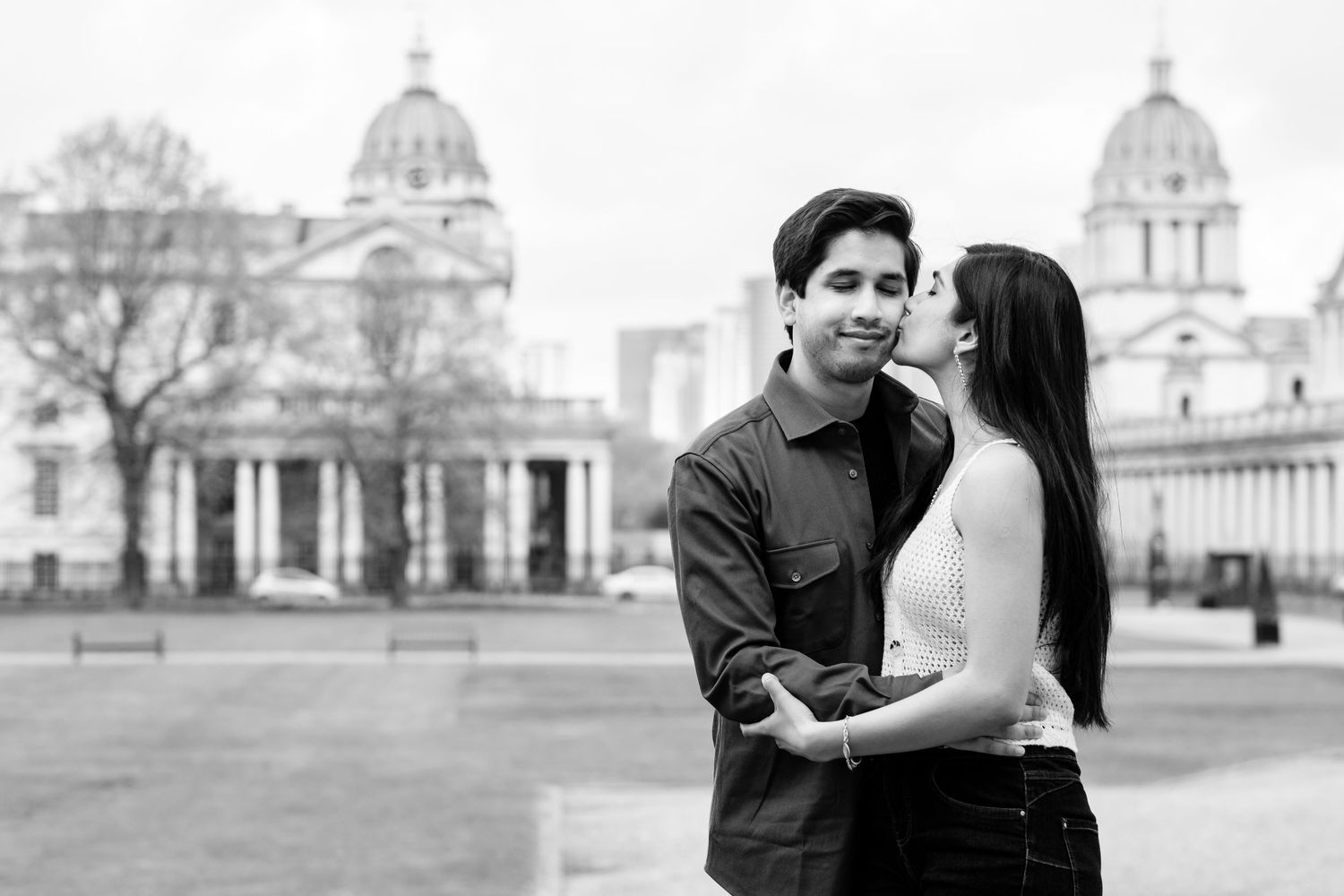 Couple sharing an intimate moment in front of historic buildings with white architecture.