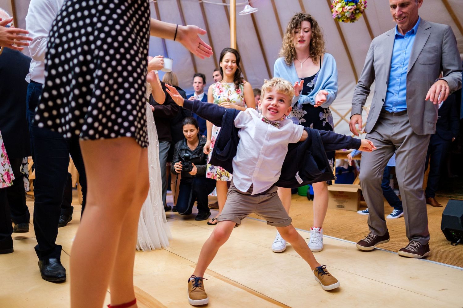 Wedding guests dance on a wooden floor during the reception celebration.