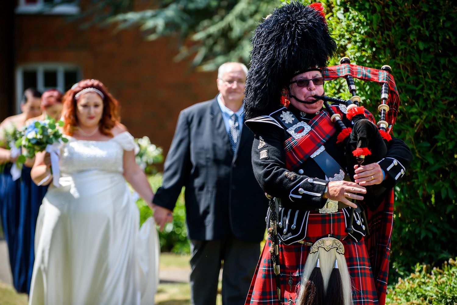 Traditional Scottish bagpiper performing at an outdoor wedding ceremony.
