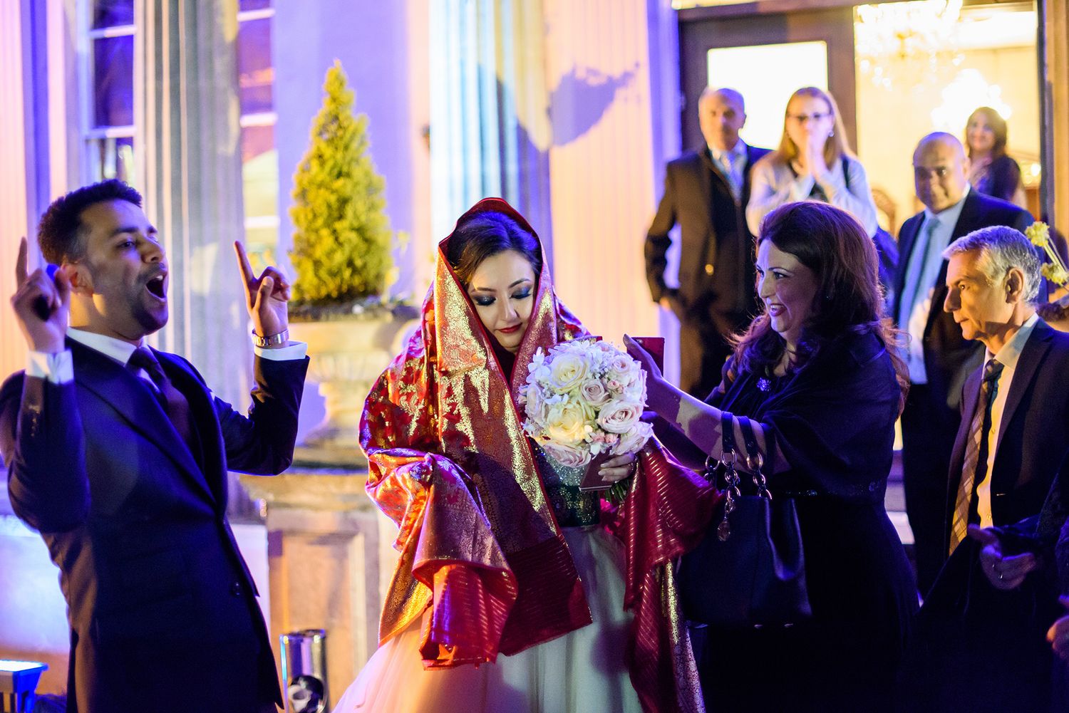 Wedding reception venue lit with purple ambient lighting and guests enjoying the celebration.