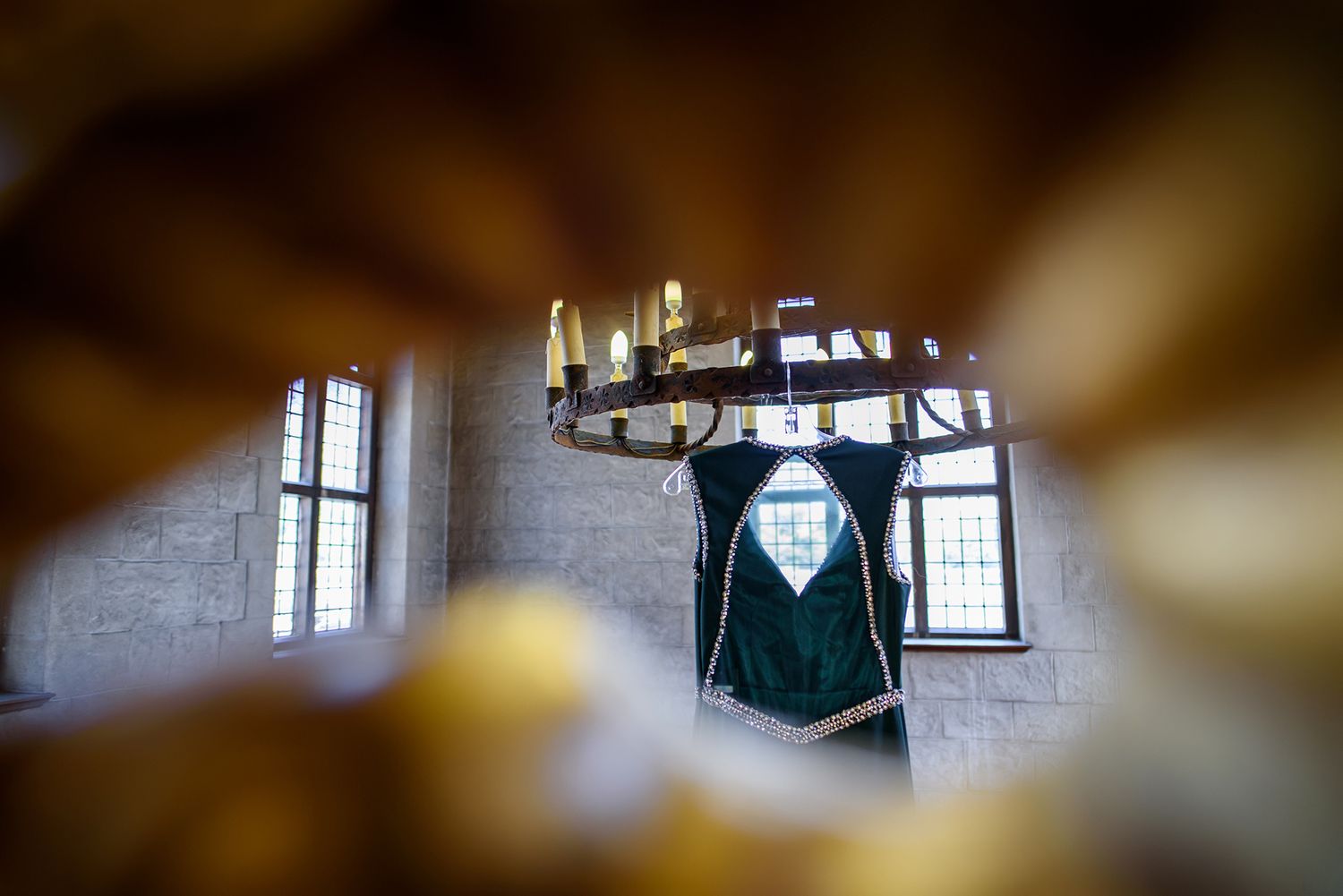 Elegant green suit jacket hanging in a vintage room with dramatic window lighting.