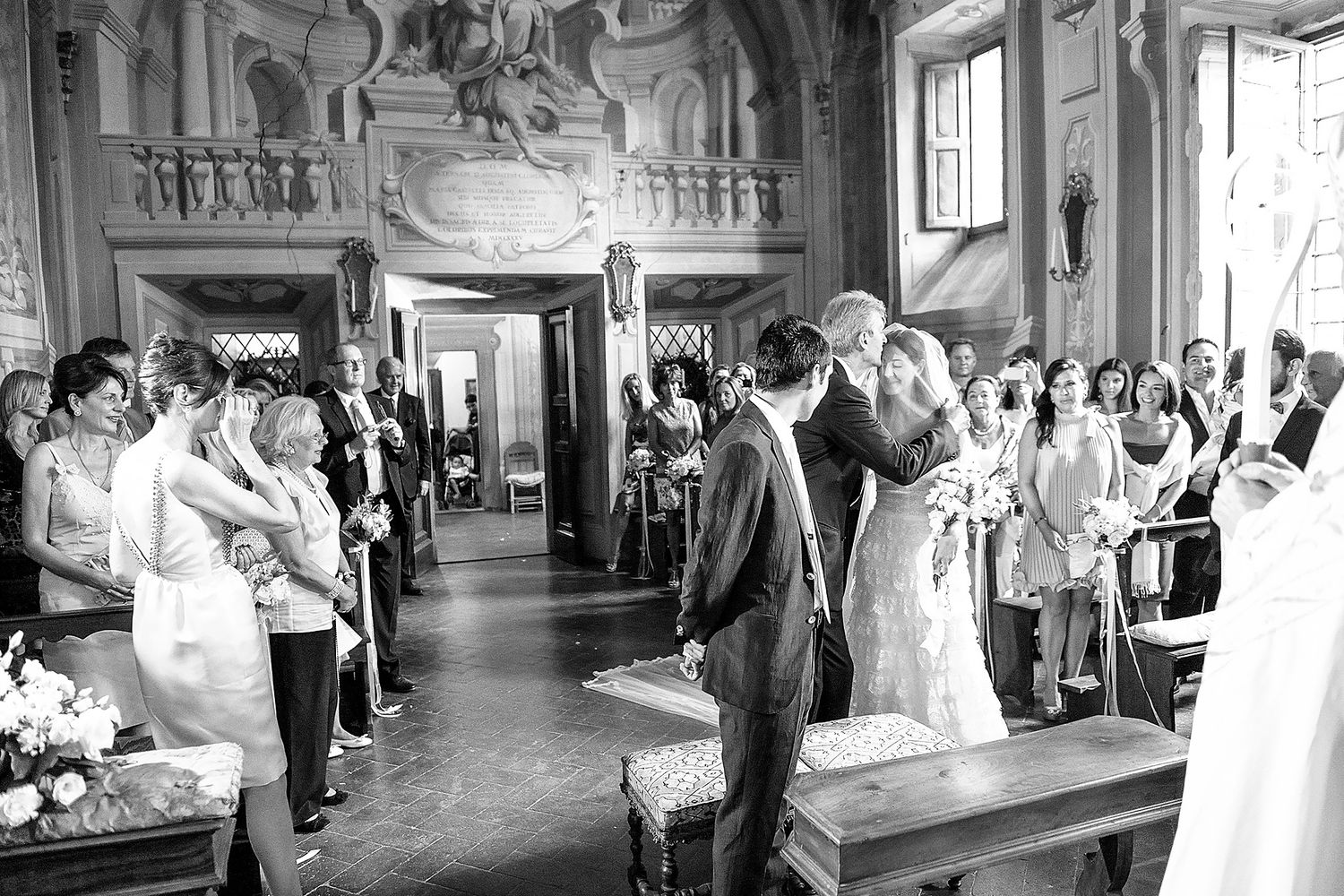 Wedding celebration in a grand historic hall with ornate painted ceilings and architecture.