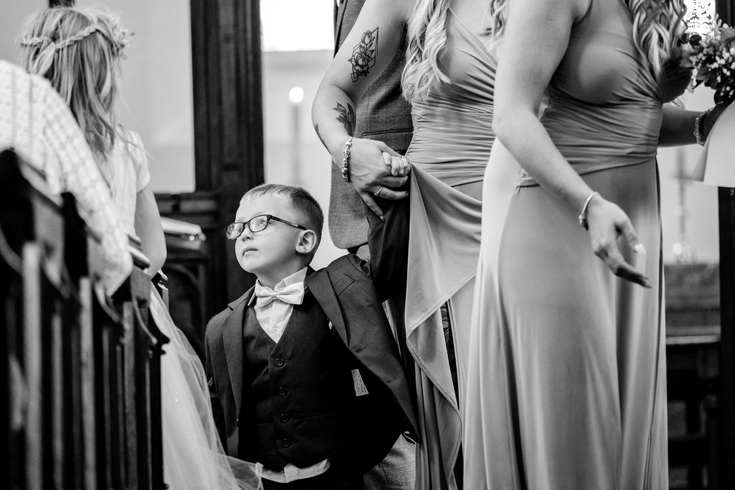 Wedding party members in gray dresses and formal attire gather for photos indoors.