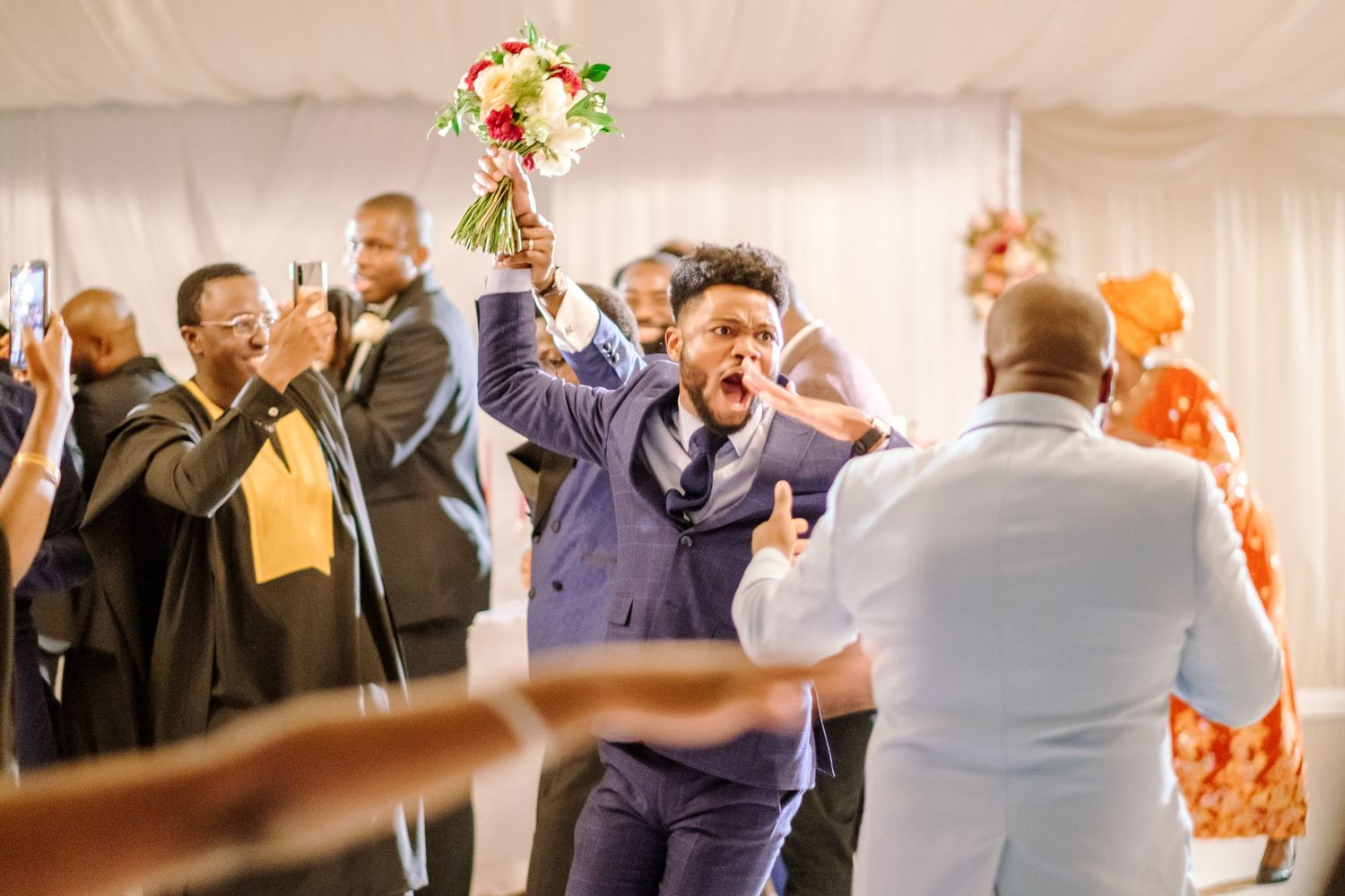 Wedding reception celebration with guests dancing and mingling under a white tent.