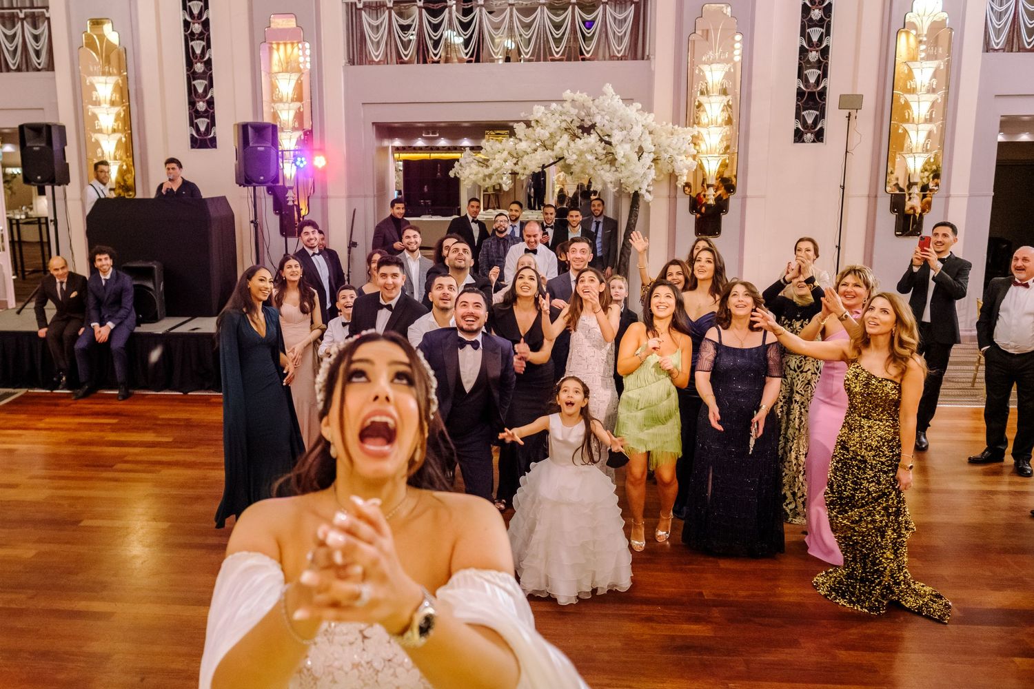 Wedding guests dance and celebrate joyfully on an elegant ballroom dance floor during an evening reception.