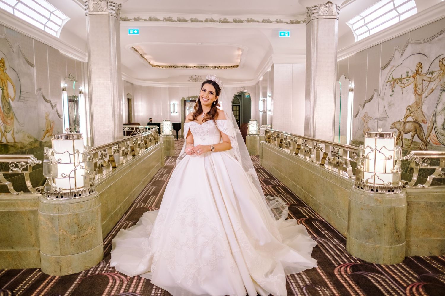 A stunning wedding photoshoot in an elegant white ballroom with ornate mirrors and decorative columns.