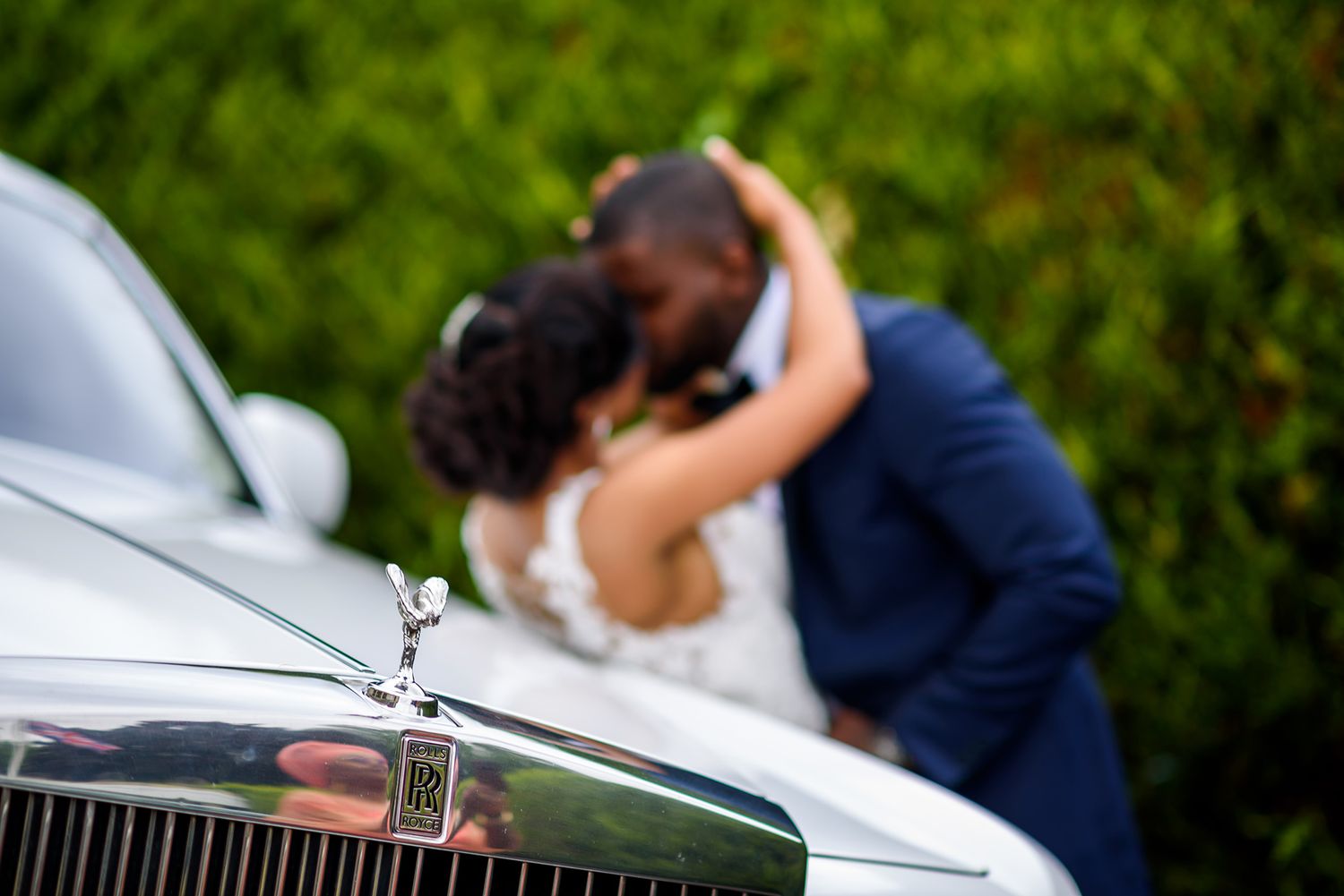Elegant wedding couple embracing next to luxury vintage car.