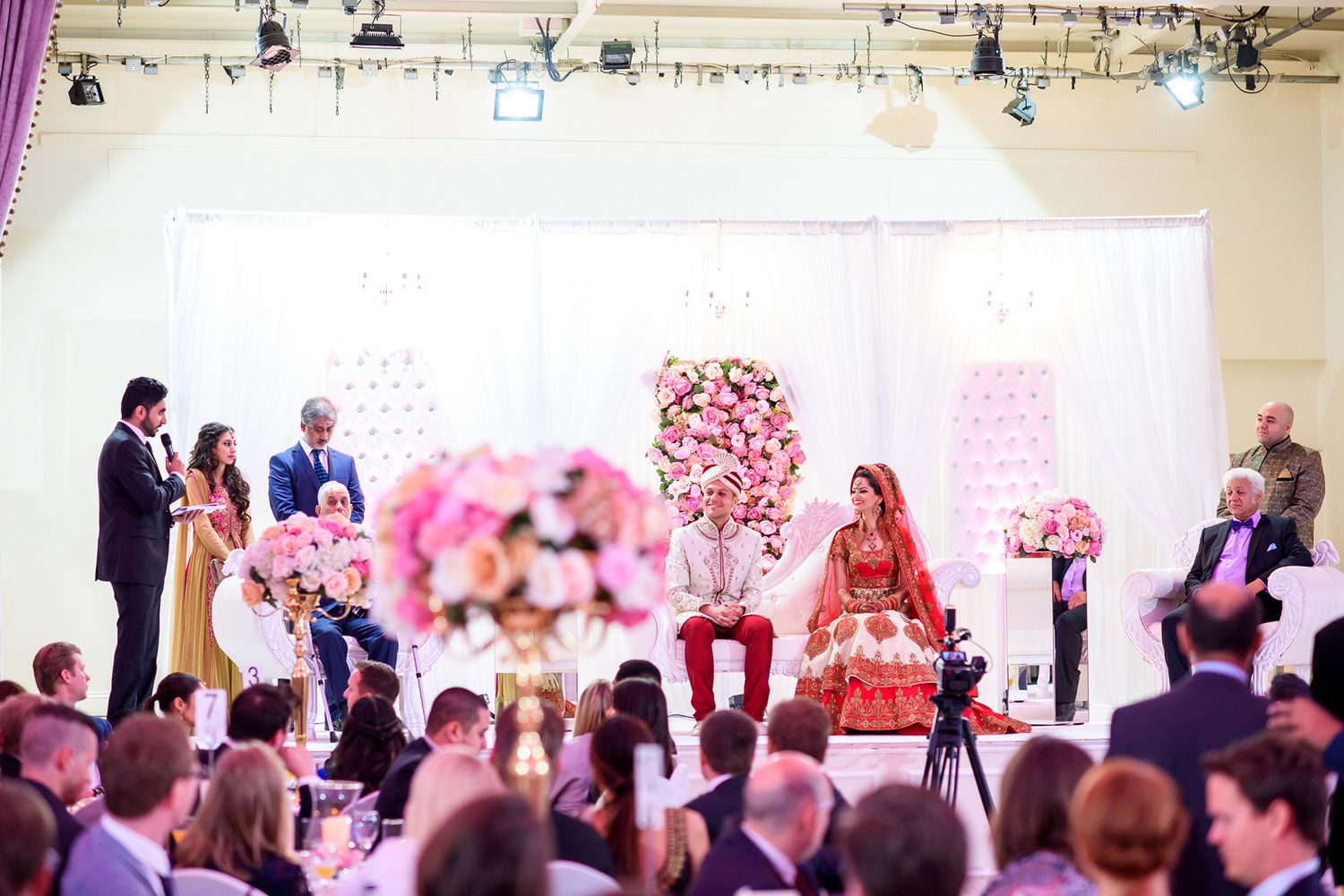Traditional wedding ceremony with pink floral decorations and gathered guests.