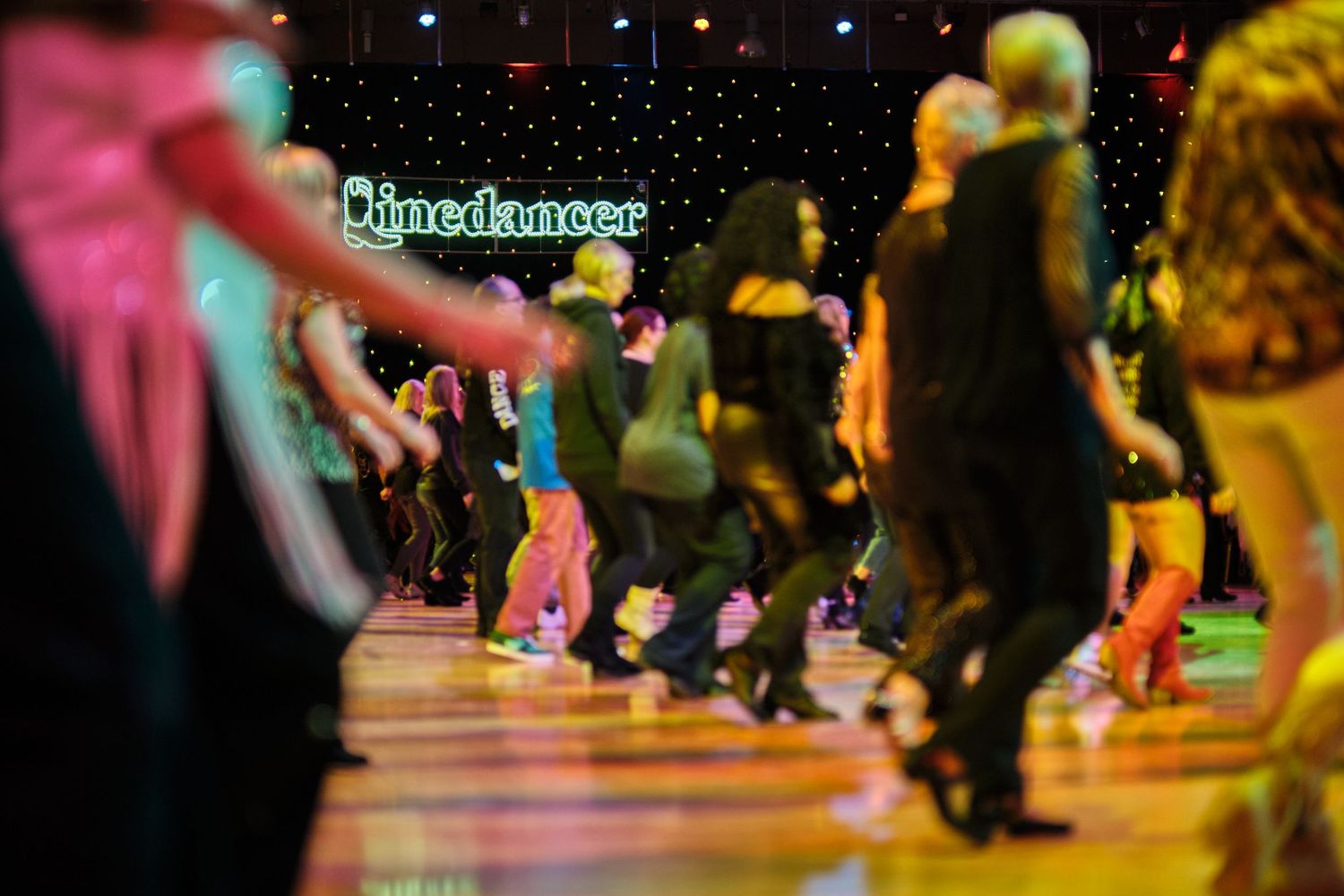 Dance floor filled with people under colorful nightclub lighting.