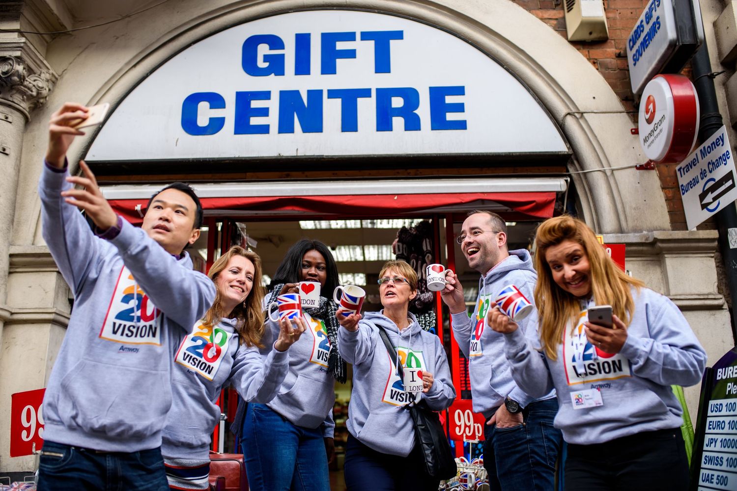 Shopping mall gift center entrance with excited people in matching gray sweaters.
