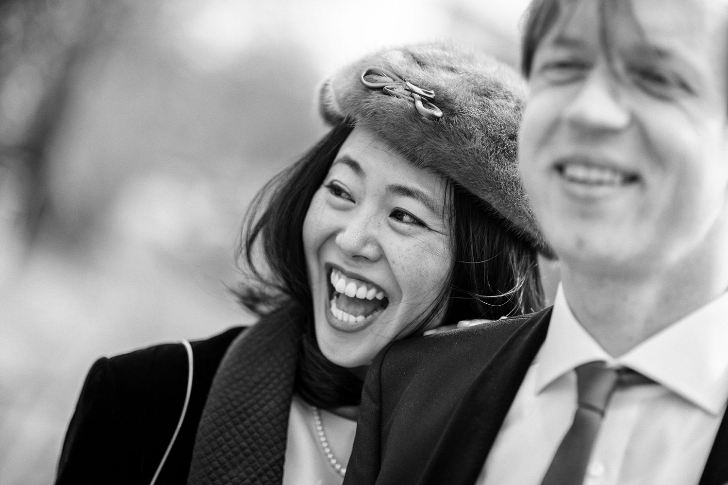 Black and white candid photograph of a couple laughing together outdoors.