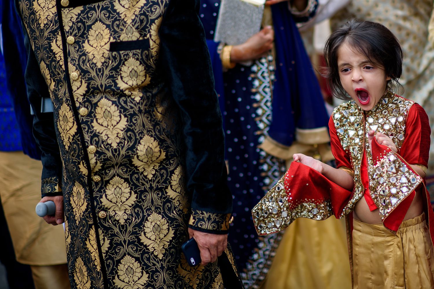 Elegant wedding guests in traditional South Asian attire with gold embroidered details.