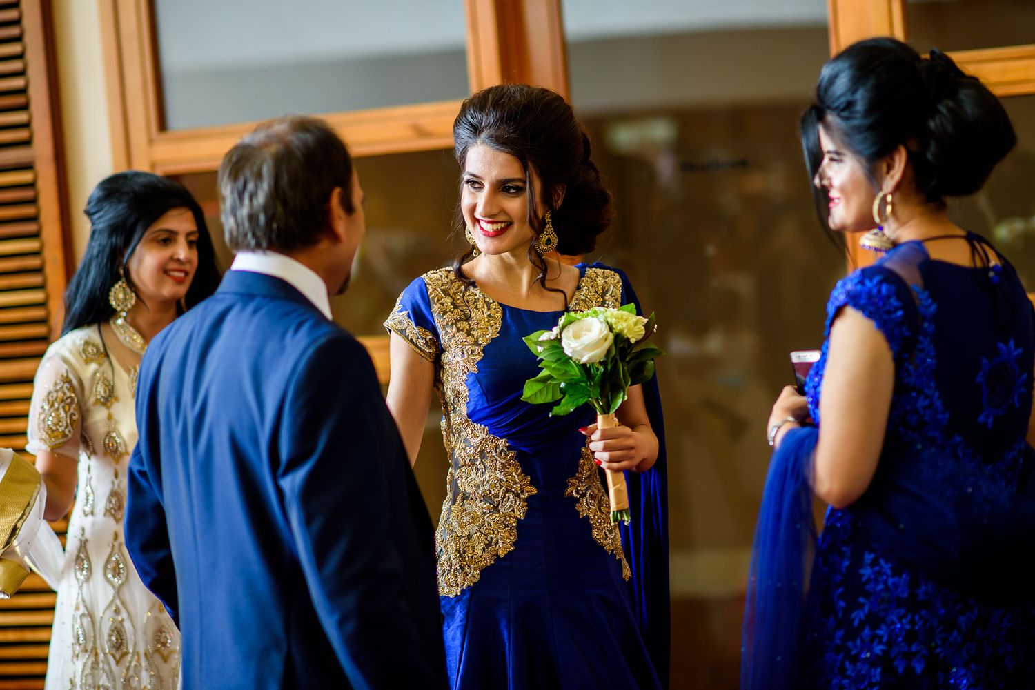 Wedding party members in royal blue and gold attire gather for formal group photos at an elegant venue.