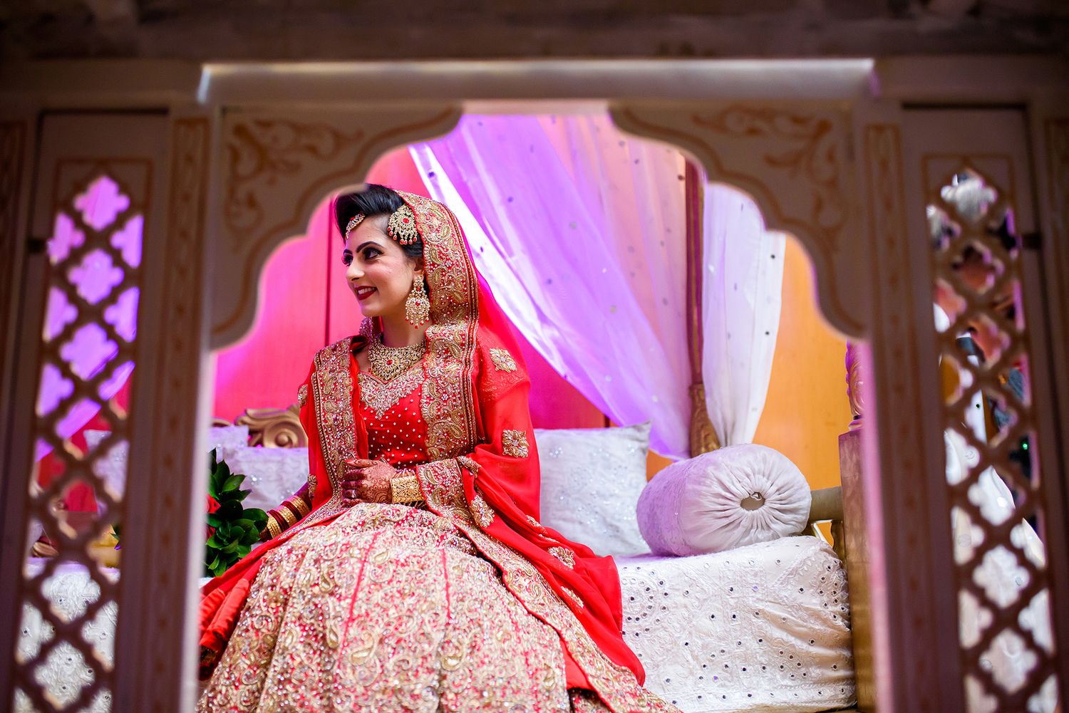 Traditional wedding ceremony with ornate decorations and pink lighting effects.