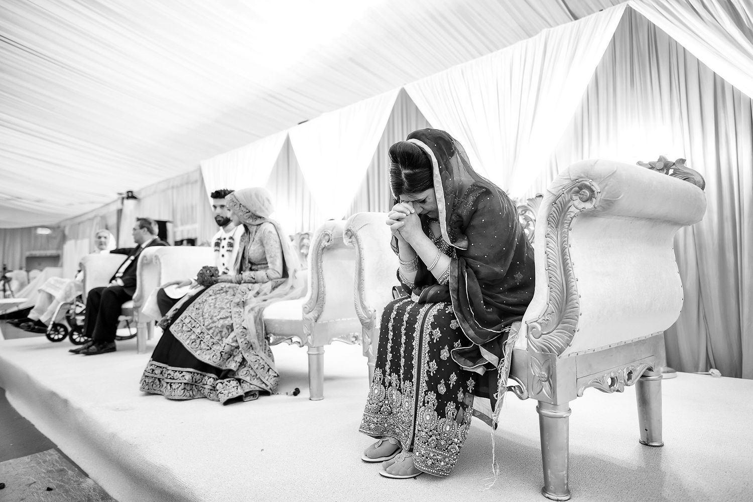 Elegant white wedding venue setup with draped fabric and floral decorations.