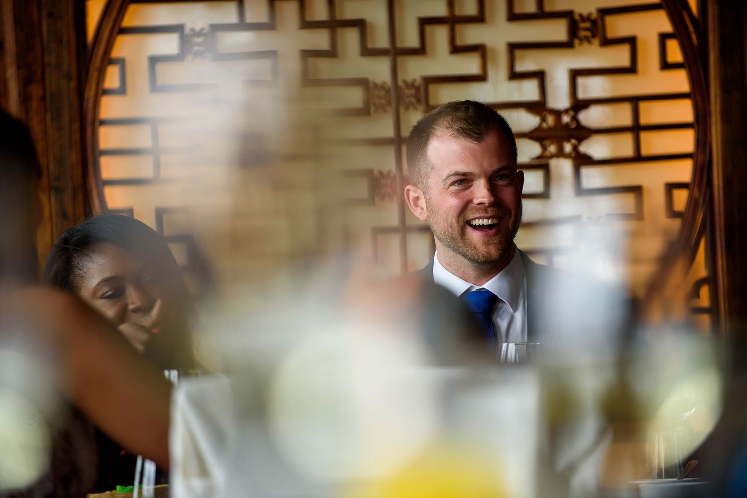Diners enjoying an elegant meal with decorative geometric patterns visible on restaurant walls.