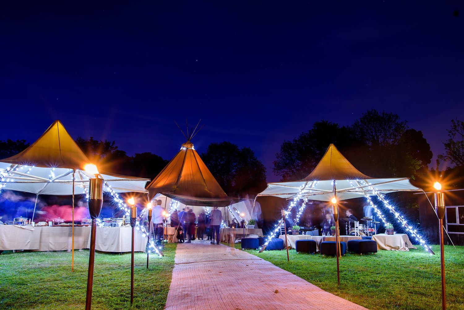 Illuminated wedding tent setup at night with festive lighting and decorations.