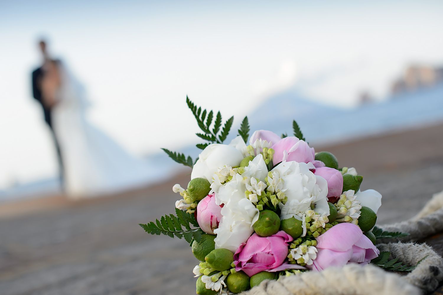 Close-up of pink and white floral wedding bouquet with greenery.