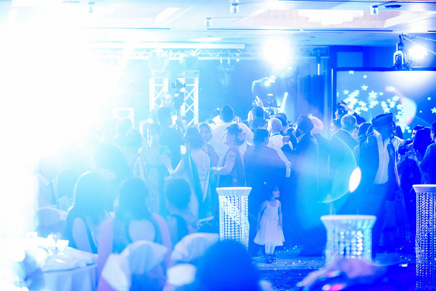 Wedding reception dance floor filled with guests under bright blue lighting effects.
