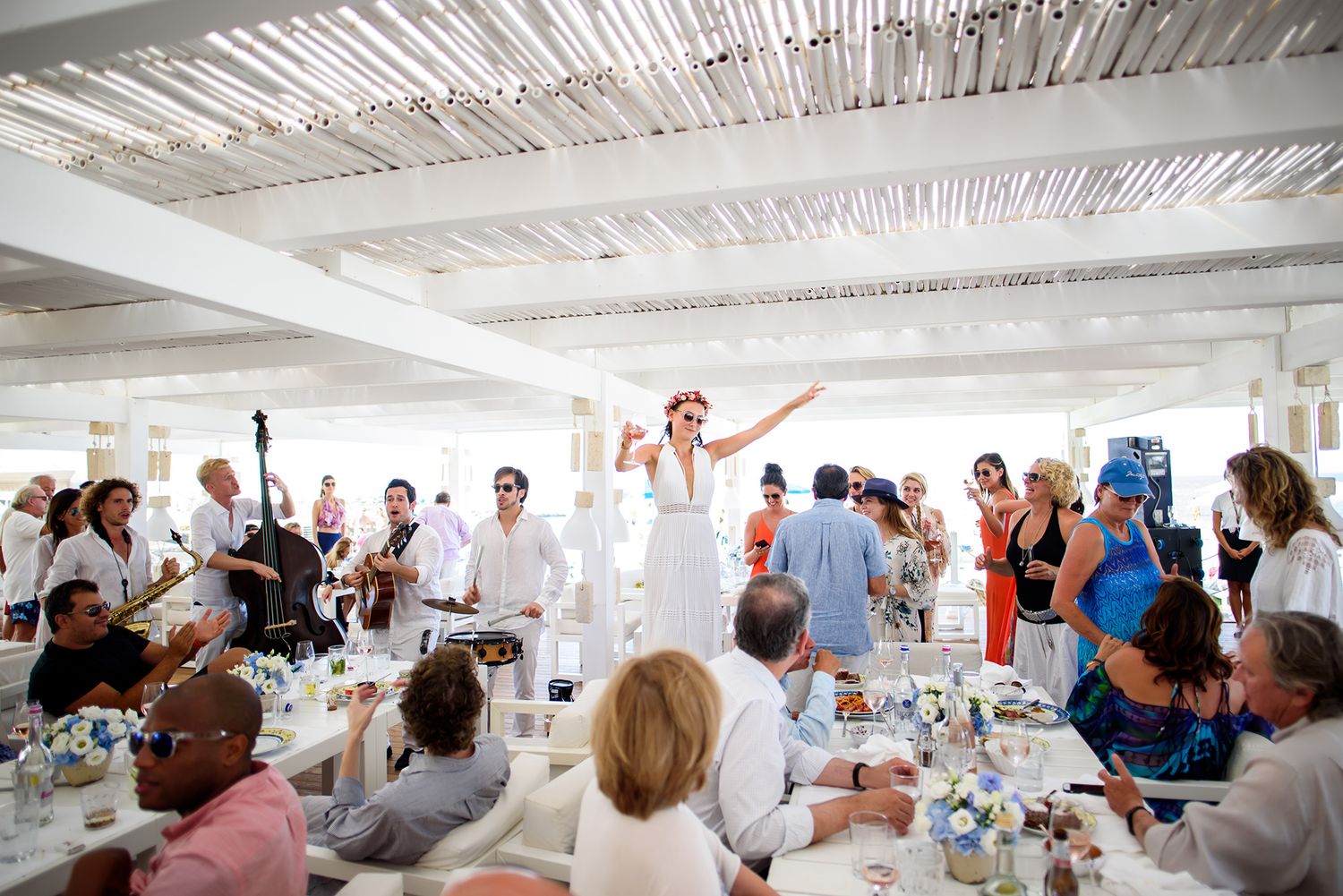 Wedding reception guests celebrate under a white tent ceiling at an outdoor venue.