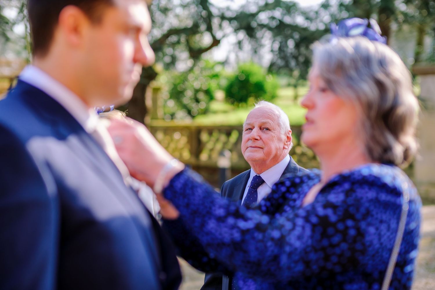 Wedding ceremony guests gathered outdoors on a sunny day with formal attire.