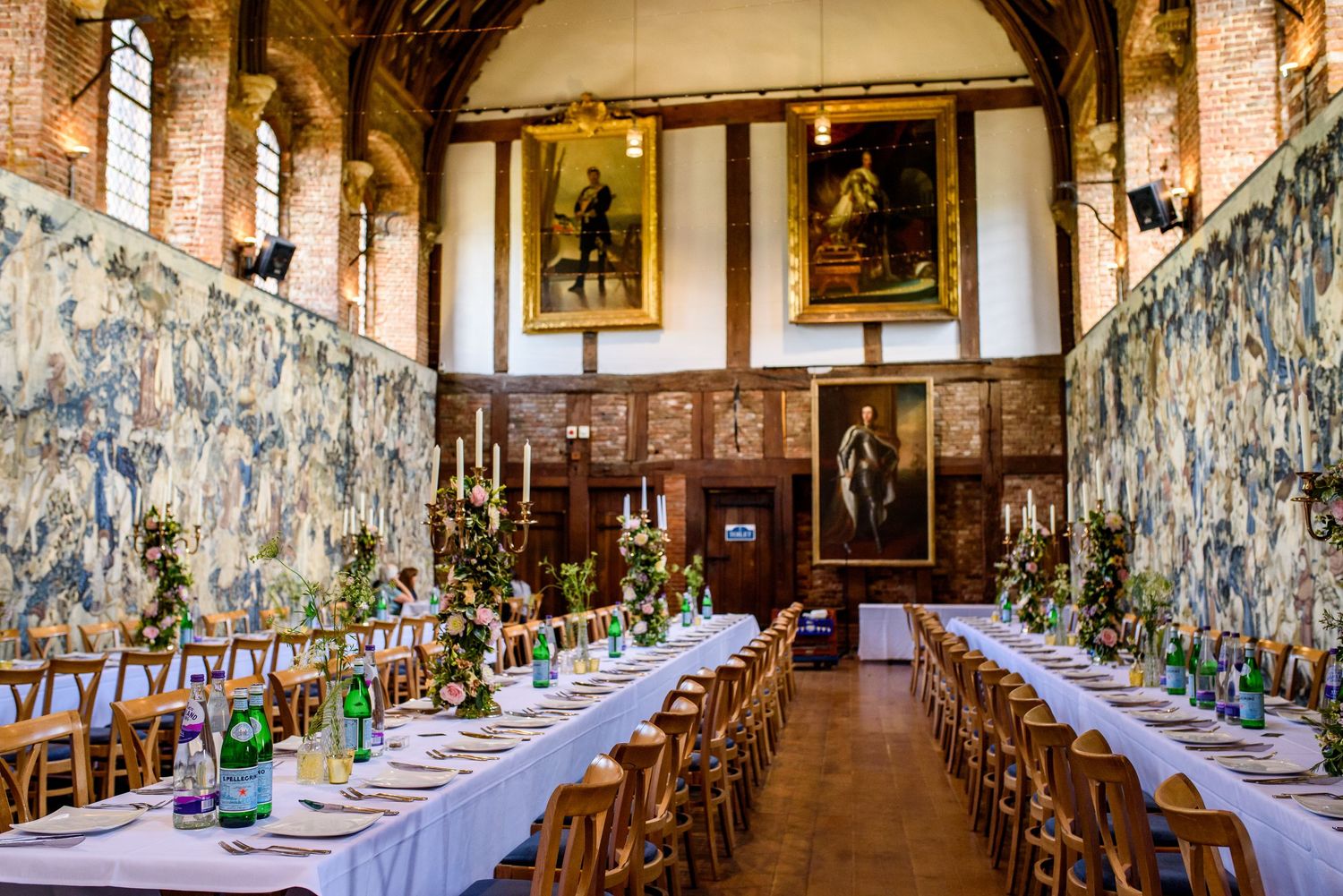 A grand medieval dining hall with vaulted ceilings and long tables set for a formal event.