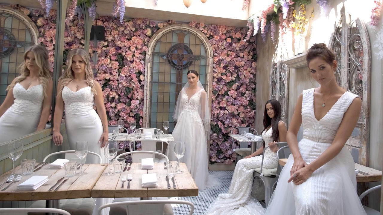 A collection of elegant white wedding dresses displayed in a bridal boutique interior.