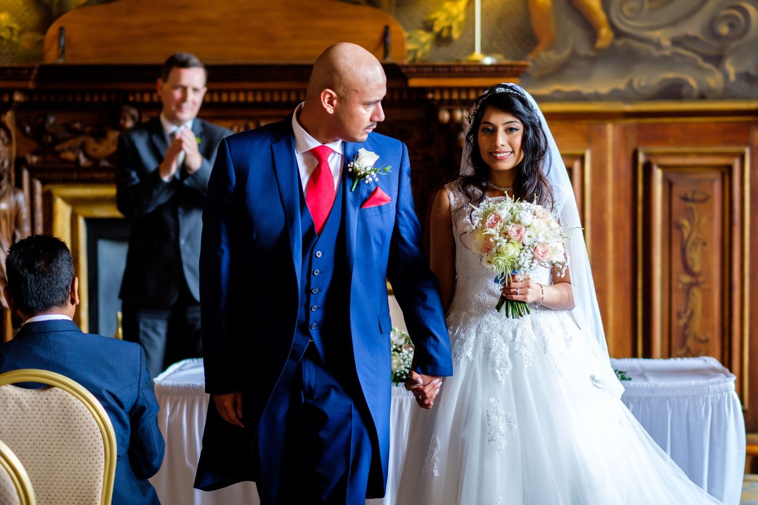A joyous wedding celebration in an elegant wood-paneled venue with ornate details.