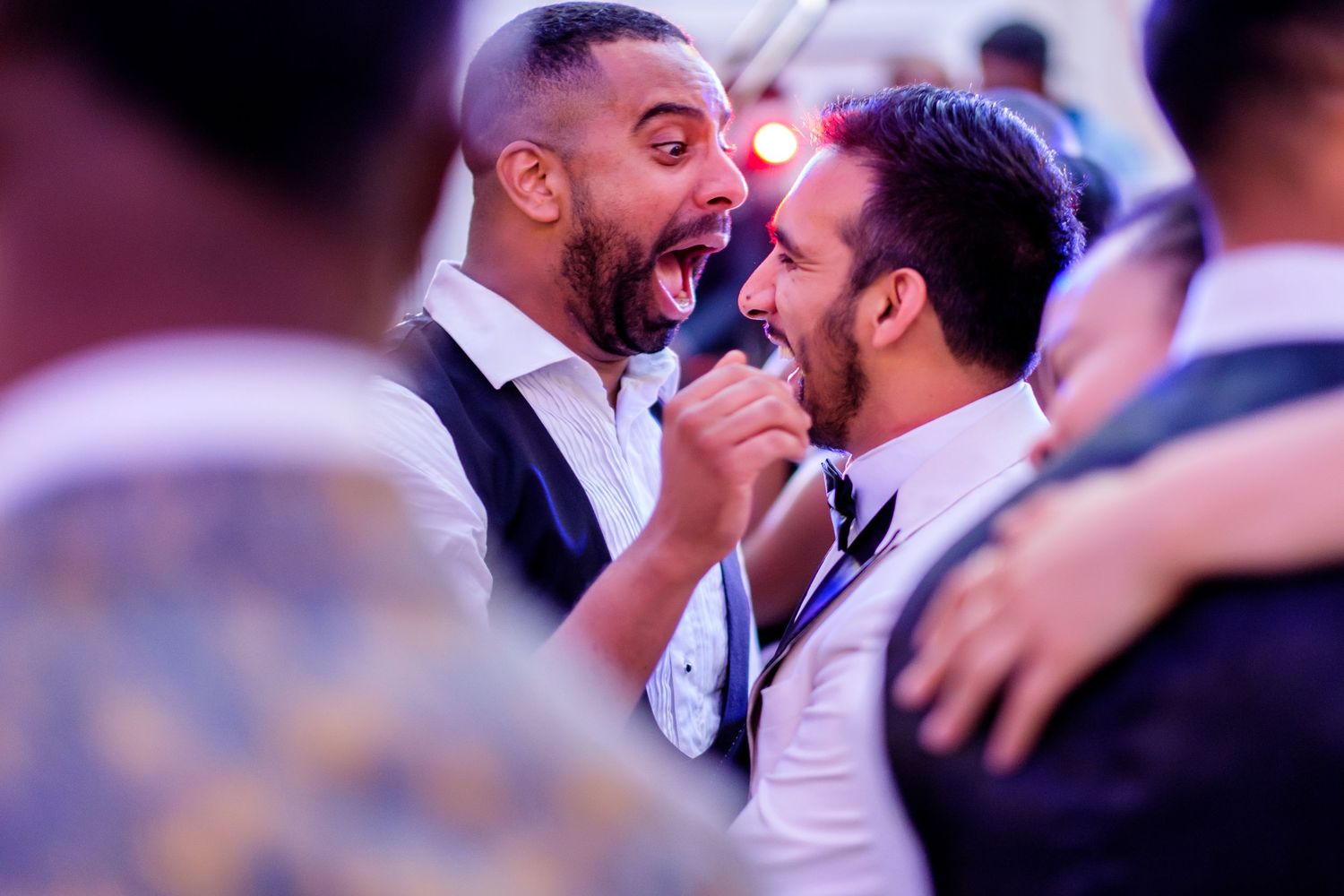 Partygoers celebrating with joyful expressions at a dimly lit reception.