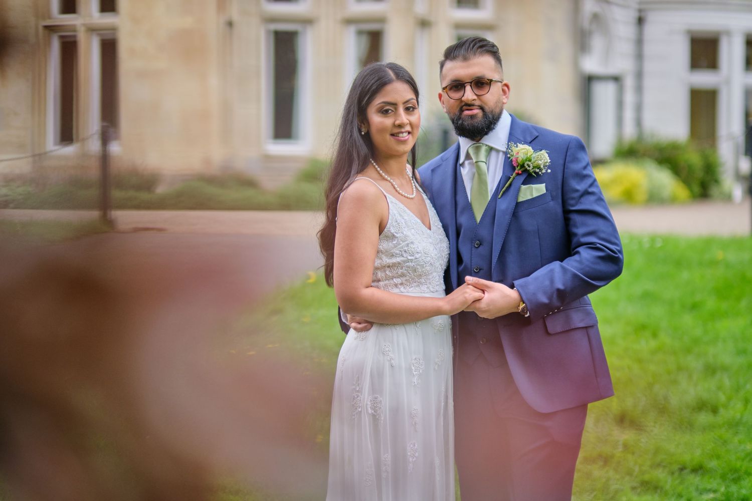Couple shares their first dance at an outdoor wedding venue with lush greenery in the background.