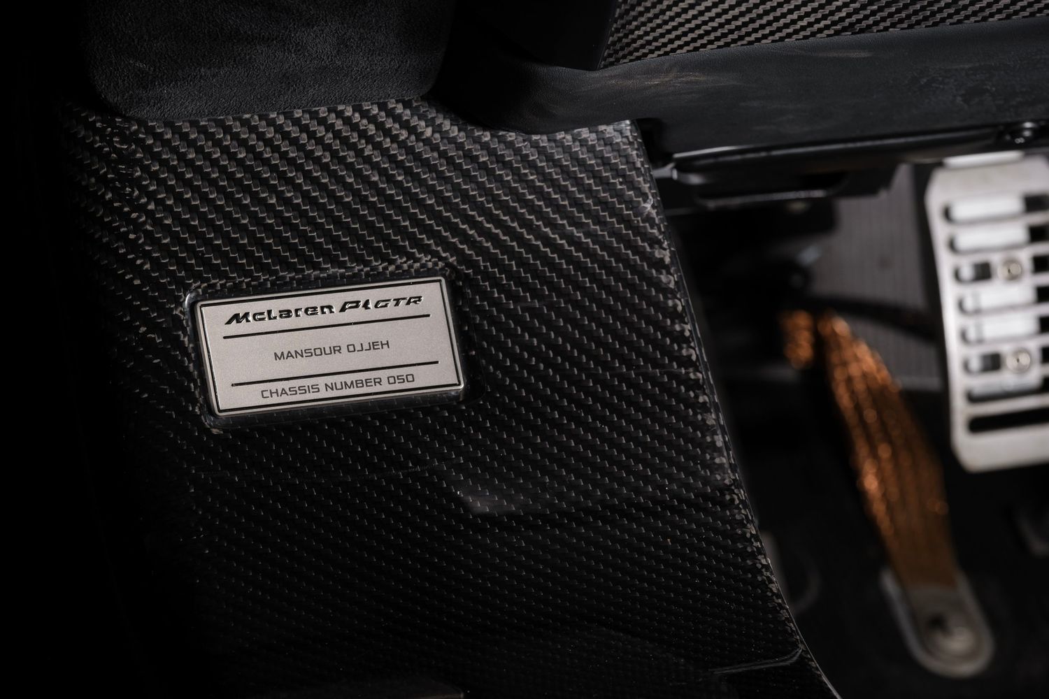 Close-up details of carbon fiber panels and trim pieces in luxury vehicle interior.