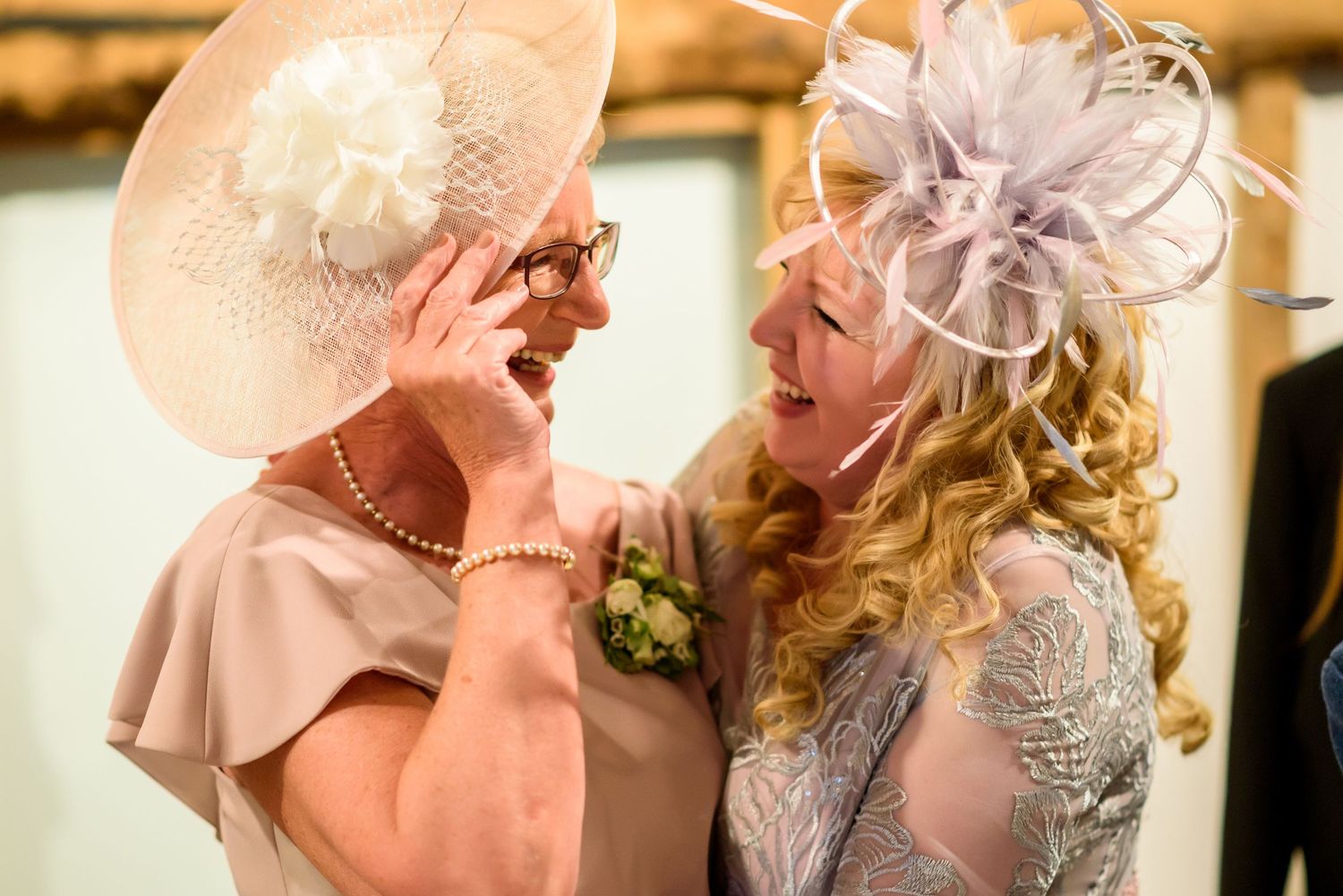 Wedding guests in elegant hats and fascinators mingle during a formal celebration.