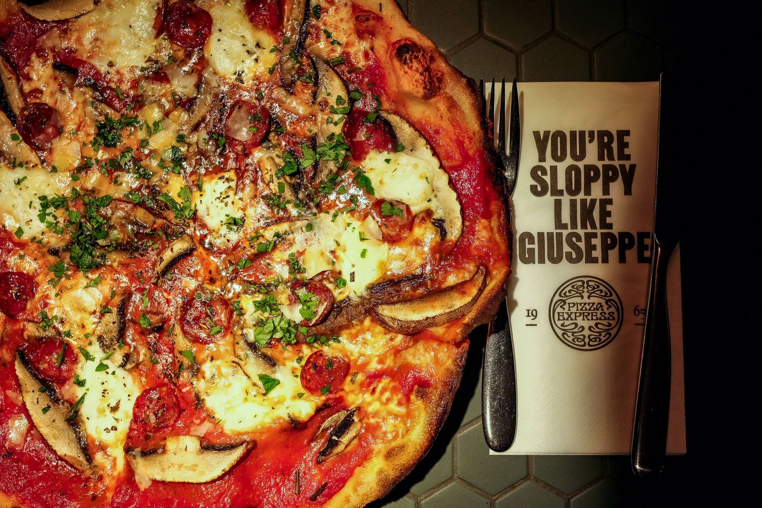 Artisanal pizza with fresh toppings displayed next to branded restaurant merchandise.