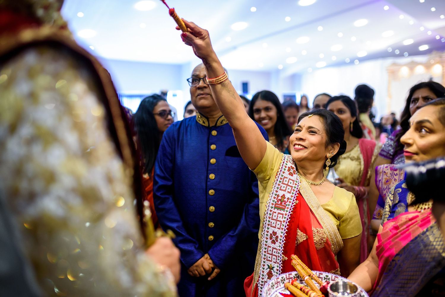 Joyful celebration at an Indian wedding with guests dancing and waving their hands in colorful traditional attire.