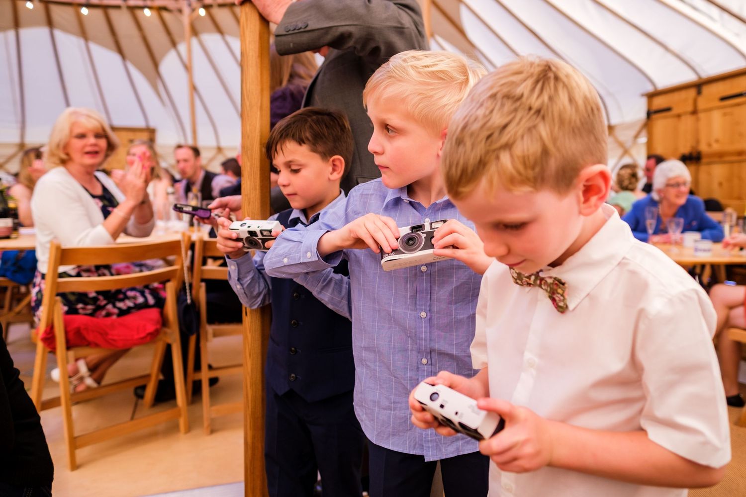 Young boys in bow ties and formal attire playing with cards at a wedding reception.