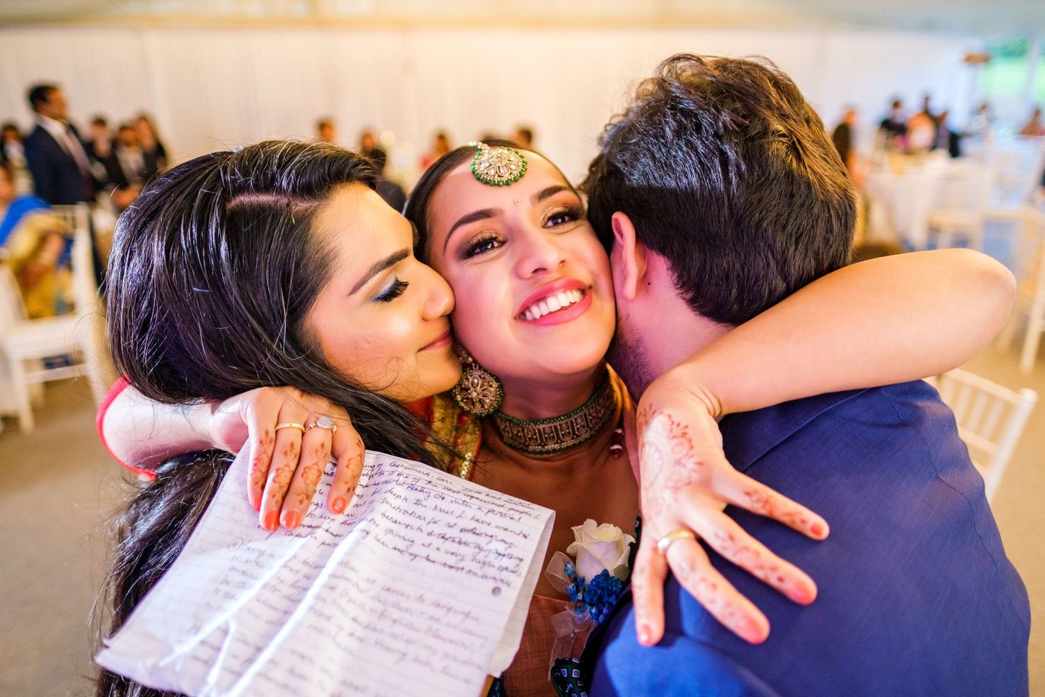 Emotional group embraces and celebrations at indoor wedding reception.