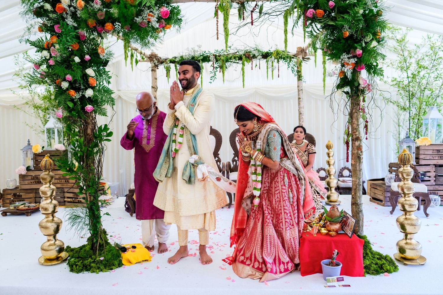 Elegant wedding ceremony decor with floral arches and traditional Indian elements in a white draped venue.